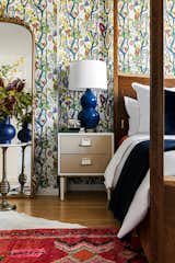 Art deco inspired nightstands from Anthropologie and royal blue table lamps from One Kings Lane flank either side of the four poster bed. The organic shape of the lamps mimic the curved and playful pattern in the Melodi wallpaper just behind. 
