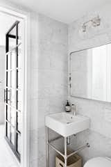 Corner sink in marble bathroom.