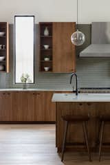 Kitchen, Pendant Lighting, Range Hood, Range, Wood Cabinet, Undermount Sink, Glass Tile Backsplashe, Engineered Quartz Counter, and Medium Hardwood Floor  Photo 8 of 14 in Lakemoore by Cecile Gottlich