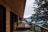 Outdoor, Decking Patio, Porch, Deck, Metal Fences, Wall, and Trees The view from the master bedroom deck down the length of the house.  Photo 12 of 14 in A Shingle-Clad Prefab Anchors Itself on Patagonia’s Largest Lake from Hats House by SAA arquitectura + territorio
