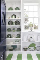 Old Grove estate pantry featuring playful green painted striped floor, built in shelving and navy swinging diner door.