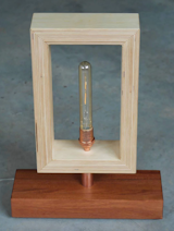 Baltic Birch Framed Copper Lamp in Jatoba Base. 
Inspired by Frank Lloyd Wright’s philosophy of Organic Architecture, we’ve designed these lights to feature clean and simple lines that  pay homage to American Minimalism, while still creating a warm and inviting interior space from the glowing reflection of an Edison bulb energized by its ceramic period reproduction socket.

To purchase:
https://toddalanwoodcraft.com/collections/lighting/products/baltic-birch-framed-copper-lamp-in-jatoba-base

Baltic Birch plywood brings a level of complexity with its layers of wood, handcrafted to complete each line at the mitered corners of the opened ended box surrounding the bulb. The beautiful base for this lamp is crafted from South American Jatoba wood famous for its gorgeous reddish-brown color and unique interlocking grain patterns. 

These two woods are joined together by a piece of copper piping, which brings out the best color elements in both woods. 

This table lamp is perfect for a Mission or modern style living room, a family room side table, or makes a cool addition to any professional’s office. These lamps would also make a great decorative practicality for a swank restaurant or bar.