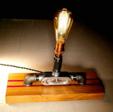 Steel and Copper with French Oak and Purple Heart Base lamp
Made from remnants of our Industrial past, this is a light that’s a re-imagined and re-purposed version of classic piping hardware. This lamp is where the antique look of copper meets the mechanical feel of aluminum and steel. 

To Purchase:
https://toddalanwoodcraft.com/collections/lighting/products/steel-and-copper-with-french-oak-and-purple-heart-base-lamp

A 40 watt Edison bulb provides a perfect warm glow to your environment in complimenting contrast to the metals used in the creation of the light.
An exquisite French Oak and Purple Heart base is created by utilizing the high quality castoff pieces from the production of our cutting, charcuterie and serving boards. This beautiful base adds a softer and warmer, welcoming atmosphere to your home or business. It’s sure to be a conversation piece. 