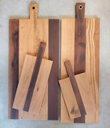 French Roasted Oak Copper Sleeve Charcuterie Boards combine both the elegant,  dark coloring of Roasted oak and the creamy highlights of French Oak, drawing out each woods naturally beautiful grain & contrasting colors.

Inlaid copper in the handle finish off the natural rustic elements and aesthetics of these boards. Its oversize hole allows the board to be hung while not in use. Available in 4 sizes.