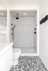 Black and white master bathrooms inside the home feature terrazzo floor tile and penny round tile surrounding the alcove showers.