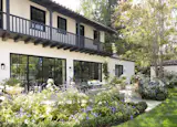 Monterey Colonial rear patio with indoor-outdoor access to kitchen and dining. Second story balcony overlooks the yard. Detached garage seen in the rear.