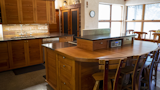 Kitchen, Concrete Floor, Recessed Lighting, Range Hood, Stone Counter, Dishwasher, Wood Backsplashe, Accent Lighting, Wood Counter, Wood Cabinet, and Cooktops Kitchen and Dining Room  Photo 10 of 34 in The Palimpsest House by Tara Lord