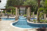 A Great American Watrerfall Company rainfall feature adds fun to the lazy river's path. A custom built cypress pergola spans the river atop stone and concrete columns. 