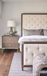 Awash in neutrals and sunlight, this guest bedroom welcomes guests with touches of soft coloration from the rug showcasing the unique wooden elements in the room.  Light from natural and illuminating sources offers a dramatic detail for guests to enjoy. The upholstered bed and complementary bench add comfort throughout the room. 