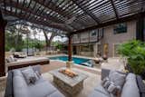 A serene lounge below a custom cypress pergola offers a comfortable viewing spot for taking in the activities in the entire outdoor space.  A stone and tile gas fire pit is surrounded by plush modular seating by Patio Renaissance. 