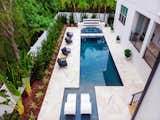 This over 1,400 square foot outdoor living space is dressed in Tahitian Pearl Marble, glass tile, and custom architectural and landscape elements by Ryan Hughes Design Build.  The Modern Pearl project, in an economy of outdoor space, perfectly illustrates glistening luxury within a bespoke retreat.  Brown Jordan lounge chairs border the pool allowing for a durable and comfortable spot for watching pool activities.  Images by Jimi Smith Photography. 