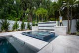 Stepping stone pavers provide a walkway adjacent to the glass tile raised spill-over spa.  The shimmering blue tile brings a brilliance in contrast to the Pearl Marble surfaces.   Matte black and white tile offers additional contrast within the soothing waterfall wall.   Images by Jimi Smith Photography. 