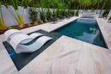 The beauty of the near 1,000 square feet of Tahitian Pearl Marble surfaces brings a soothing and elegant connection to all areas of the outdoor design.   Ledge Lounger chaise lounges with canopies adorn the sun shelf of this pool. 
Images by Jimi Smith Photography. 
