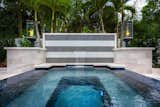 Matte black and white tile are presented in an elegant striped waterfall wall display. Grand Effect helix torches stand guard over the designer water feature atop Pearl Marble cladded walls.  Vidrepur - Titanium tile completely covers the raised spill-over spa and offers a perfect spot to take in the gentle waterfall.  Images by Jimi Smith Photography.
