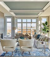 In the living room, the plan was to allow for gatherings around the fireplace or the television while also capturing the waterside views.  Ceiling niches were designed to incorporate motorized solar shades from Lutron that disappear when not in use.  A custom colorized rug defined the space while not competing with the surroundings.  Furnishings from Tomlinson Companies to Alfonso Marina were coordinated with lighting from the artisans of Visual Comfort and Hammerton.