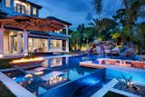 Outdoor, Large Patio, Porch, Deck, Back Yard, Boulders, Hardscapes, Trees, Concrete Patio, Porch, Deck, Large Pools, Tubs, Shower, Tile Patio, Porch, Deck, Planters Patio, Porch, Deck, Swimming Pools, Tubs, Shower, Infinity Pools, Tubs, Shower, Concrete Pools, Tubs, Shower, Decking Patio, Porch, Deck, and Landscape Lighting Outdoor lighting by PAL offers relaxation and a swim under the stars once the sun goes down. A custom linear American Fireglass fire feature is built pool-side for greater ambiance. The adjacent Ledge Loungers on the sun shelf offer a perfect visual point for watching all activities in the outdoor living space.   Photo 4 of 10 in Keystone Falls by Laurie Rudd