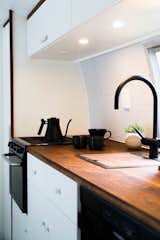 The kitchenette is an exercise in space efficiency; a handmade walnut insert covers the sink to maximize counter space. 