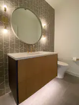 Powder room features a Henrybuilt vanity, Blu Dot mirror, Schoolhouse electric lighting, floor-to-ceiling tile and Kohler fixtures.