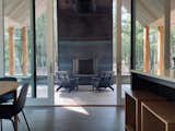 The cabin's massive sliding windows open to the covered porch, extending the great room outside. Modern adirondack chairs from Loll surround the wood burning fireplace.
