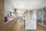 Prep  gourmet meals with ease in a custom kitchen with large center island, marble countertops and backsplash, and top-of-the-line stainless steel appliances (Miele and Sub-Zero).
