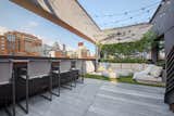 Outdoor, Rooftop, Shrubs, and Hanging Lighting This oasis is just as incredible at night, with lovely lighting and dazzling city skyline views.  Photo 5 of 9 in A Brooklyn Penthouse With Three Terraces by Halstead Real Estate