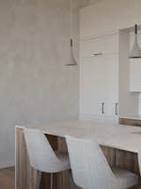 A close-up of the kitchen showcases a lime-painted wall that adds warmth and texture to the space. The soft, pale marble countertop complements the minimalist design, creating an elegant and serene atmosphere where natural materials take center stage.