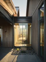A close-up of the glass walkway bathed in sunlight, with beams filtering through the transparent structure. The surrounding landscape, lush and untouched, is framed perfectly, enhancing the feeling of serenity and harmony between the home and its environment.