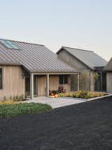 The entrance showcases a harmonious mix of natural materials—steel roofing, wooden cladding, and organic landscaping. The minimalist design enhances the home’s connection to its environment, creating a seamless transition between architecture and nature.