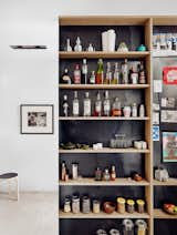 The entryway is tucked behind a thin steel wall, shielding it from the kitchen. The designers created a six-inch shelf on the kitchen side for storage.