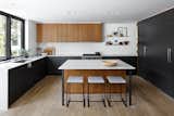 The interior wall of the kitchen that contains the refrigerator and pantry happened to line up with a side window, so it stops short of extending the length of the space, creating an opening that visually and acoustically connects the kitchen and dining room. 