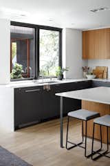 The kitchen features custom cabinetry by Ferris Co, rift and quarter sewn white oak floors, and Caesarstone counters. By pushing the screened-in porch off of the house, the structure does not block the window, allowing for more light. "While you're at the sink working in the kitchen, you can see these huge oak trees above you," says Scott.