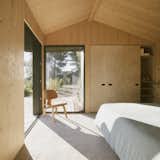 Bedroom, Bed, Storage, Chair, and Concrete Floor The main bedroom features corner windows that lead out to a small deck.  Photo 5 of 14 in A Tiny Cabin Enhances a Family Retreat on the Edge of a Pine Forest in Southern France
