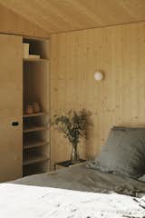 Bedroom, Shelves, Wall Lighting, Bed, and Accent Lighting "We took inspiration from the surrounding woodland landscape, seeking to create interiors that worked with the senses allowing occupants to truly relax,  Photo 6 of 14 in A Tiny Cabin Enhances a Family Retreat on the Edge of a Pine Forest in Southern France