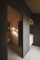 Bath Room, Concrete Floor, and One Piece Toilet A matte black finish on interior walls balances the bright Mediterranean light and offers a visual respite.  Photo 7 of 14 in A Tiny Cabin Enhances a Family Retreat on the Edge of a Pine Forest in Southern France