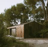 Exterior, Cabin Building Type, Gable RoofLine, and Wood Siding Material Native landscaping by Tamaris Desing incorporates palms and tussocks to further integrate the structure into the land.  Photo 4 of 14 in A Tiny Cabin Enhances a Family Retreat on the Edge of a Pine Forest in Southern France