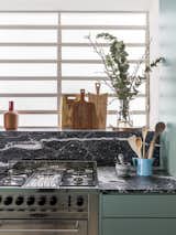 After: The nero marquina countertops are paired with hardware-free cabinetry painted a muted turquoise.