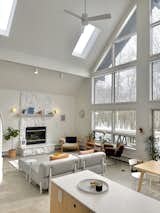 Large-format tiles give the look of polished concrete, while the fresh coat of white paint on the walls, beams, trim, and fireplace allows the wall of windows to fully illuminate the Scandinavian inspired living room.