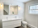 This white bathroom features floor-to-ceiling tiles that start in the shower and wrap the entire room.