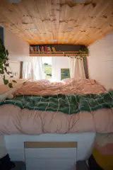 A bookshelf above the bed also holds space for greenery.