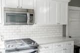 Kitchen, Microwave, Range, Subway Tile Backsplashe, White Cabinet, Engineered Quartz Counter, and Wood Cabinet Kitchen  Photo 7 of 49 in Secret Garden by Mackenzie Reynolds