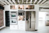 Kitchen, Wood Cabinet, Microwave, White Cabinet, Refrigerator, Wall Oven, Terrazzo Floor, and Marble Counter Kitchen Appliances  Photo 4 of 31 in Frindle by Mackenzie Reynolds