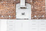 Kitchen, Brick Backsplashe, Terrazzo Floor, Cooktops, White Cabinet, Marble Counter, Range Hood, and Wood Cabinet Kitchen  Photo 11 of 31 in Frindle by Mackenzie Reynolds