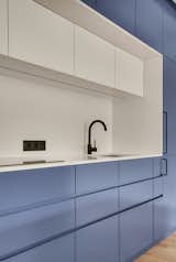 Blue and white custom made kitchen with black details (door handles, tap, and electrical outlet)