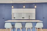 Blue and white custom made kitchen with invisible doors and pendant lightings , with black details (door handles, tap, and electrical outlet)