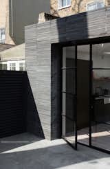 The extension connects to the patio via black steel-framed glass doors that can be opened in warm weather.