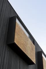 The extension is clad in charred black timber, which contrasts to the lighter, existing weatherboard structure. Graphic timber screens over the windows offer shading and privacy.