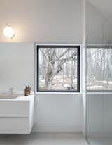 A window in the bathroom frames the surrounding forest. These smaller windows have been designed to be read as two-dimensional artworks that are part of the wall.