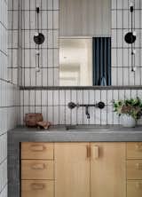 The shared bathroom features warm, natural finishes, including concrete, timber, and ceramic tile.