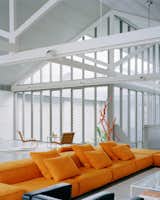 The original timber trusses are a dominant element in the living space. They had been painted white during an earlier renovation, and the design team decided to repaint them instead of stripping them back to raw timber. A new corrugated steel ceiling has been inserted between the trusses. Small perforations in the steel absorb sound into the acoustic insulation installed above.