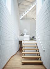 A half flight of stairs leads from the entrance to the living area. The multiple levels—connected by open-riser timber stairs and ramps—give the illusion of a much larger space.